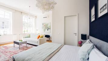 A modern bedroom with a large bed, a white sofa, a coffee table, and a chandelier.