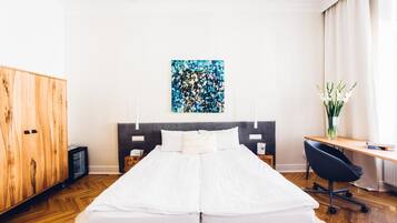 A bedroom with a bed, a desk, a chair, a wardrobe, and a painting on the wall.