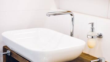 Ein Badezimmer mit Waschbecken, Wasserhahn aus Chrom und einem Holzlagerflächen.