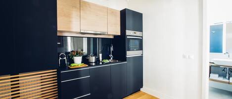 A modern kitchen with black cabinets, a stainless steel range hood, and a fruit bowl on the counter.