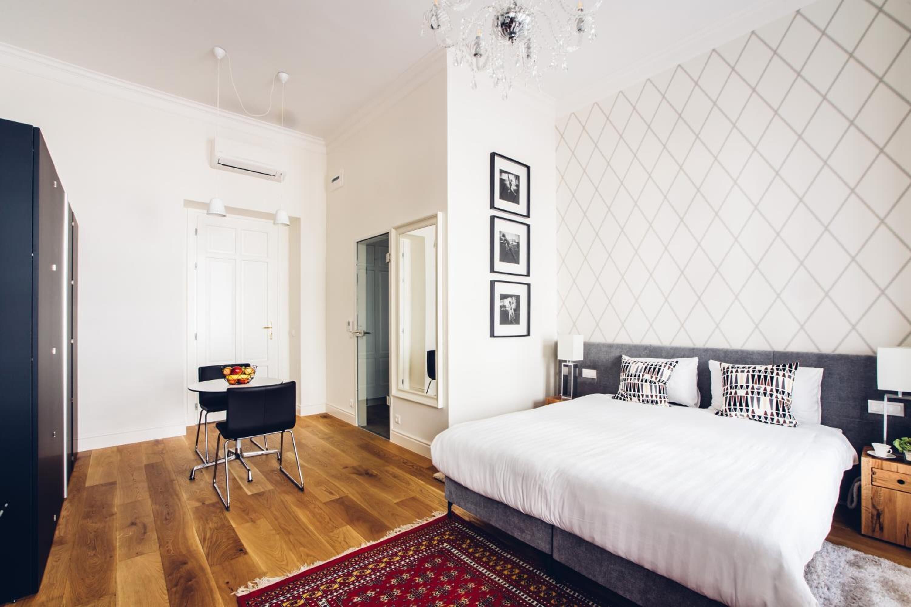 A modern bedroom with a large bed, a desk, and a chandelier.