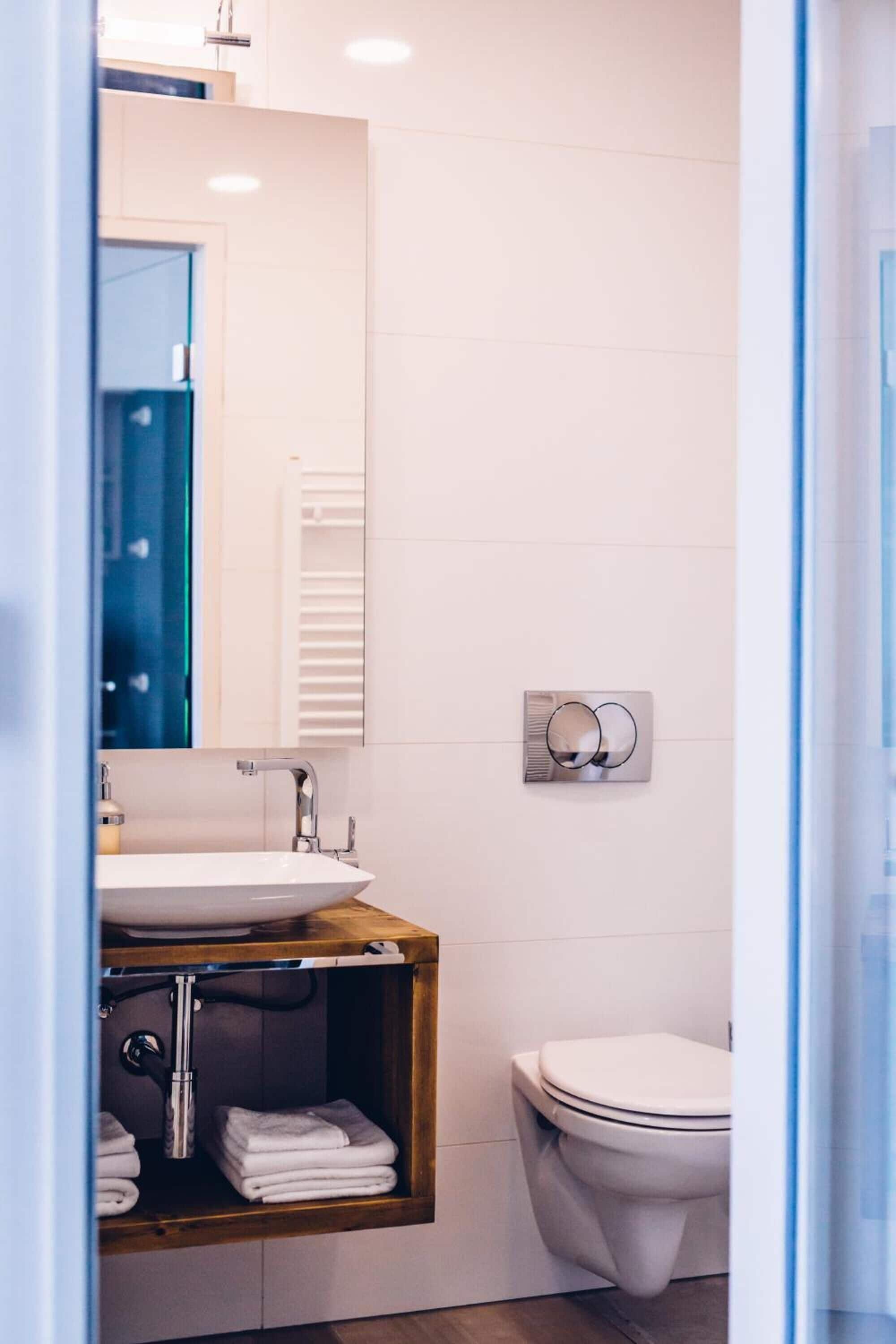 Et moderne badeværelse med vask, spejl og toilet.