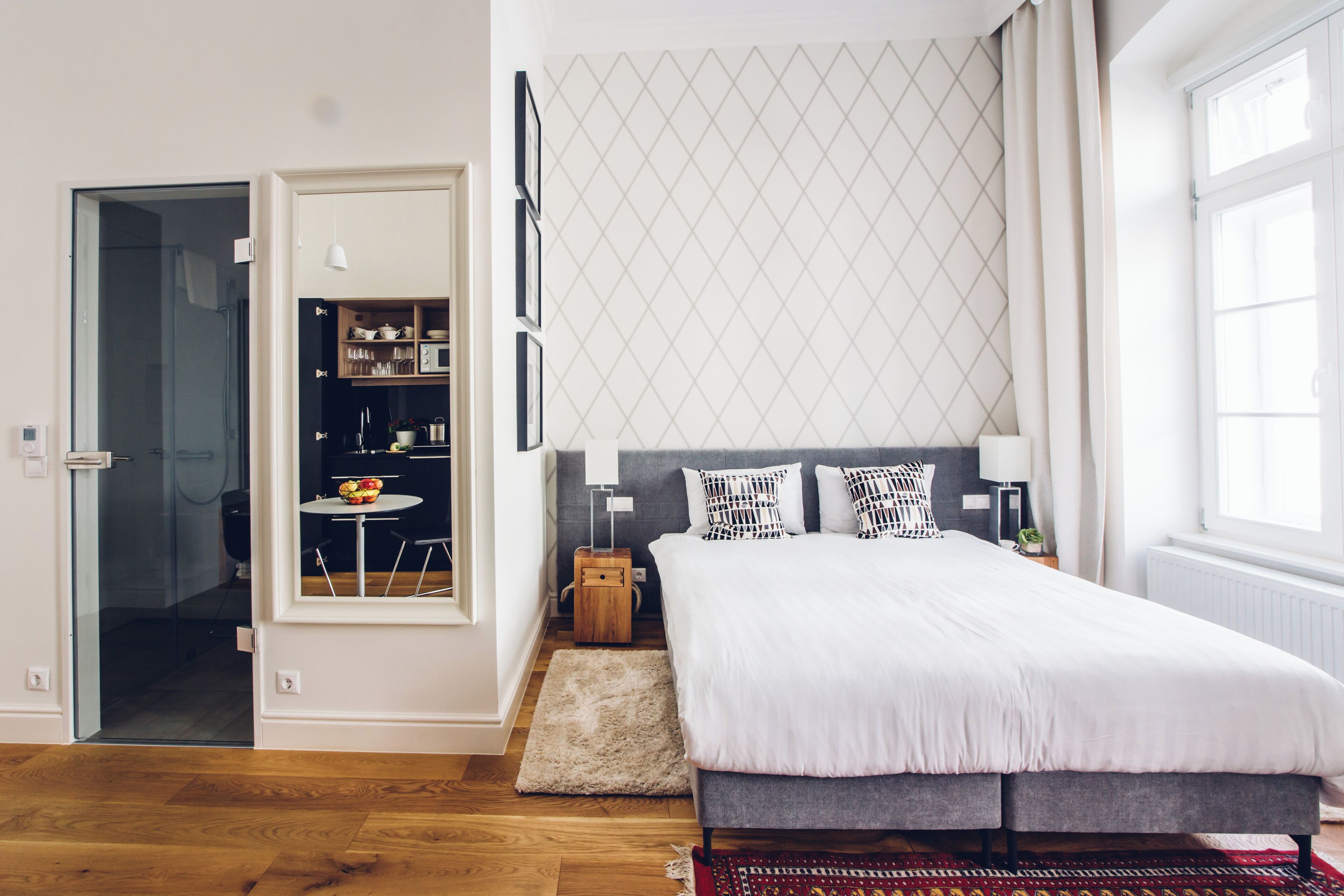 Un dormitorio moderno con una cama grande, una mesita con fruta, un armario y una ventana con cortinas.