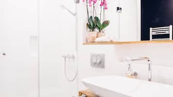 A modern bathroom with a glass shower enclosure, a white sink, and a wooden vanity.