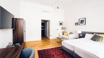 Una habitación de hotel moderna con un escritorio de madera, una cama con ropa de cama blanca, una alfombra roja estampada y un candelabro.