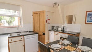A compact kitchen with a dishwasher, microwave, and a dining area set for four.