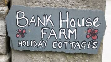 Señalización para 'Bank House Farm Holiday Cottages' con mariposas decorativas.