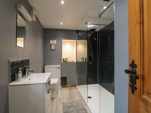 A modern bathroom with a glass-enclosed shower, a white sink, and a toilet.