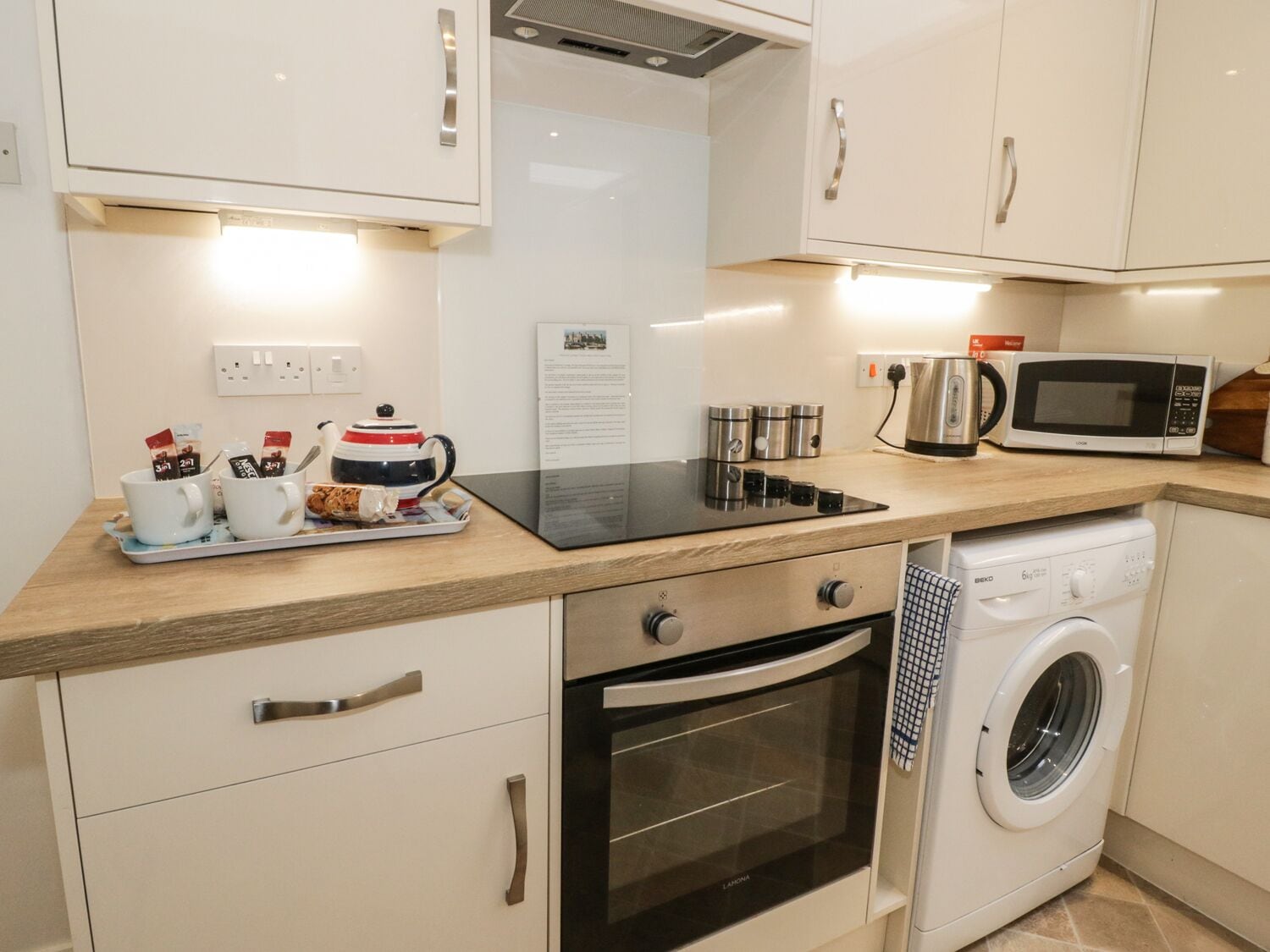 A compact kitchenette with a microwave, oven, and washing machine.