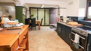 Una cocina compacta con zona de comedor, un microondas, una estufa y un reloj en la pared.