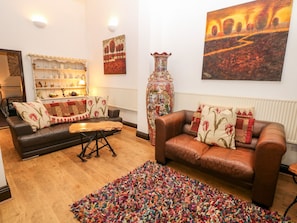 Un salon avec deux canapés en cuir, un tapis aux couleurs vives, une table basse en bois et un vase décoratif.
