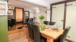 Comedor con mesa y sillas de madera, un jarrón con flores y decoración rústica.