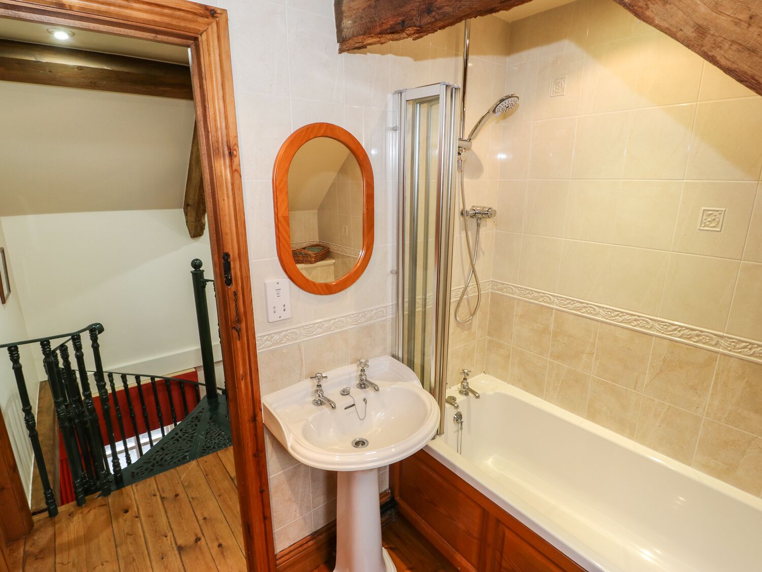 A bathroom with a wooden floor, a white sink, a bathtub, and a shower.