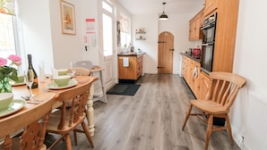 Una cocina con armarios de madera, una mesa de comedor con sillas y un refrigerador.