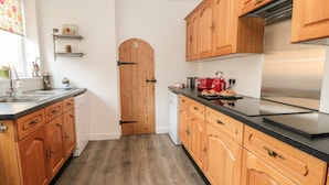 Una cocina con armarios de madera, un refrigerador de acero inoxidable y una encimera negra.