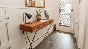 Una consola de madera con un espejo, una lámpara y una planta en maceta.