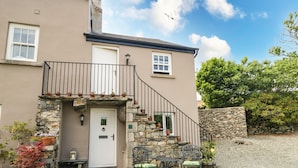 Une maison à deux étages avec une façade en pierre, un balcon et une allée gravillonnée.