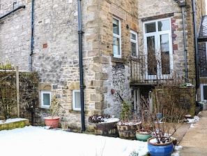 A stone building with multiple windows, a balcony, and potted plants. - 32A (Buxton)