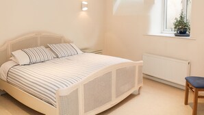 Un dormitorio con cama, ventana con planta y radiador.