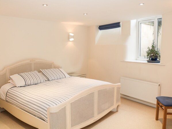 A bedroom with a bed, a window with a plant, and a radiator. - 32A (Buxton)