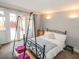 Un dormitorio con cama con dosel, una mesita de noche y un pequeño banco.