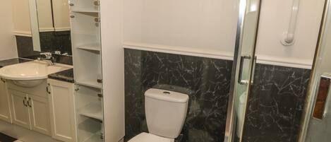 Un baño con inodoro, lavabo y cabina de ducha de vidrio.