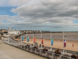 Un paseo marítimo con vistas al mar, un muelle y edificios al fondo.