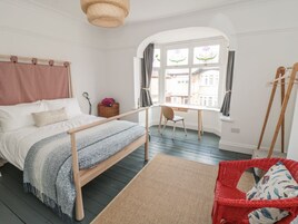 Un dormitorio con una cama, un escritorio, una silla y un sillón de mimbre rojo.
