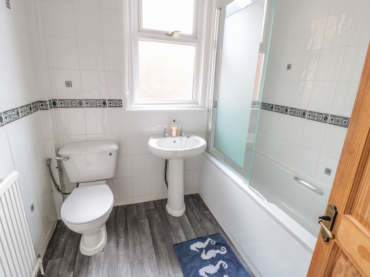 A bathroom with a toilet, sink, and glass shower enclosure.