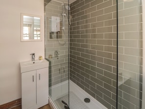 Een badkamer met een douchecabine van glas, een wit wastafelmeubel en een spiegel.