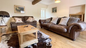 A living room with two sofas, a coffee table, and a cowhide rug. - The Coach House (Llanrwst)