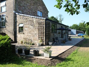 A stone building with a patio area featuring outdoor seating and potted plants.