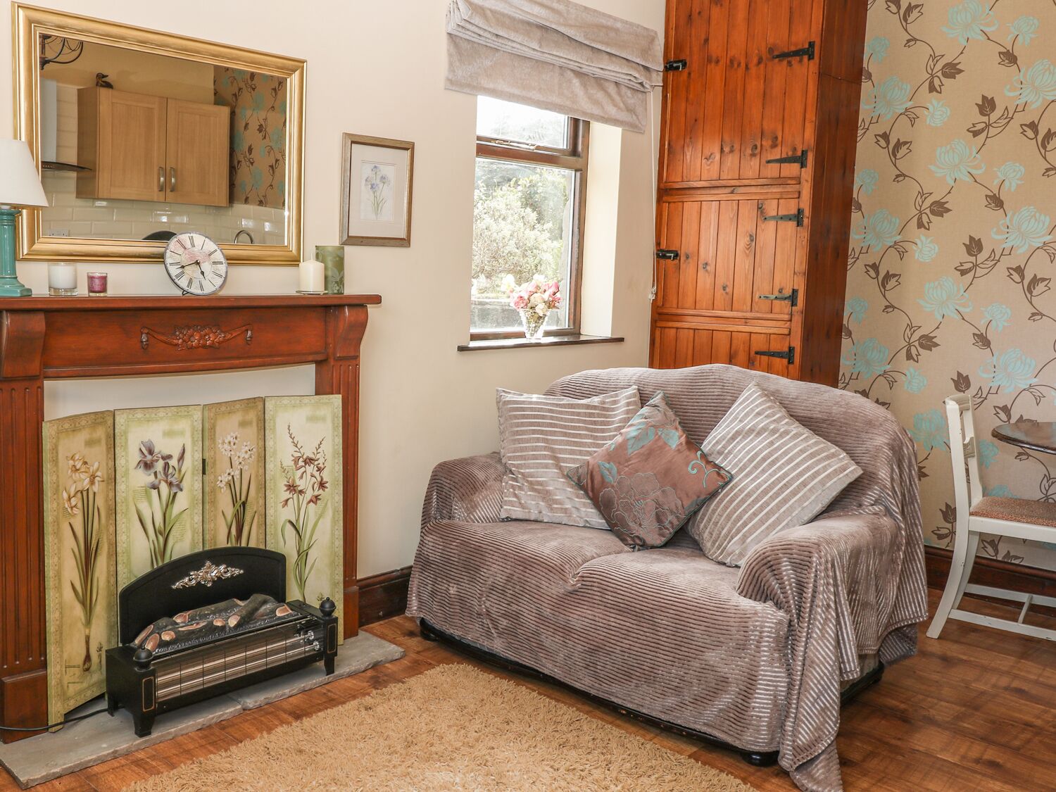 A cozy living room with a sofa, a vintage radio, a fireplace, and a wooden cabinet.
