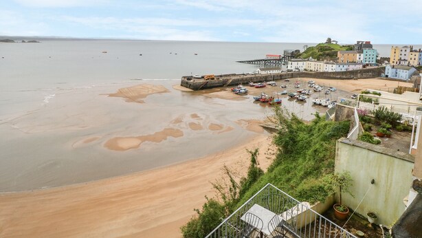 A coastal town with a sandy beach, a pier, and buildings along the shore. - Apartment 2 (Tenby)