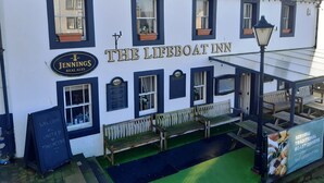 The Lifeboat Inn with a signboard, benches, and a small outdoor seating area. - Harbour Side (Maryport)