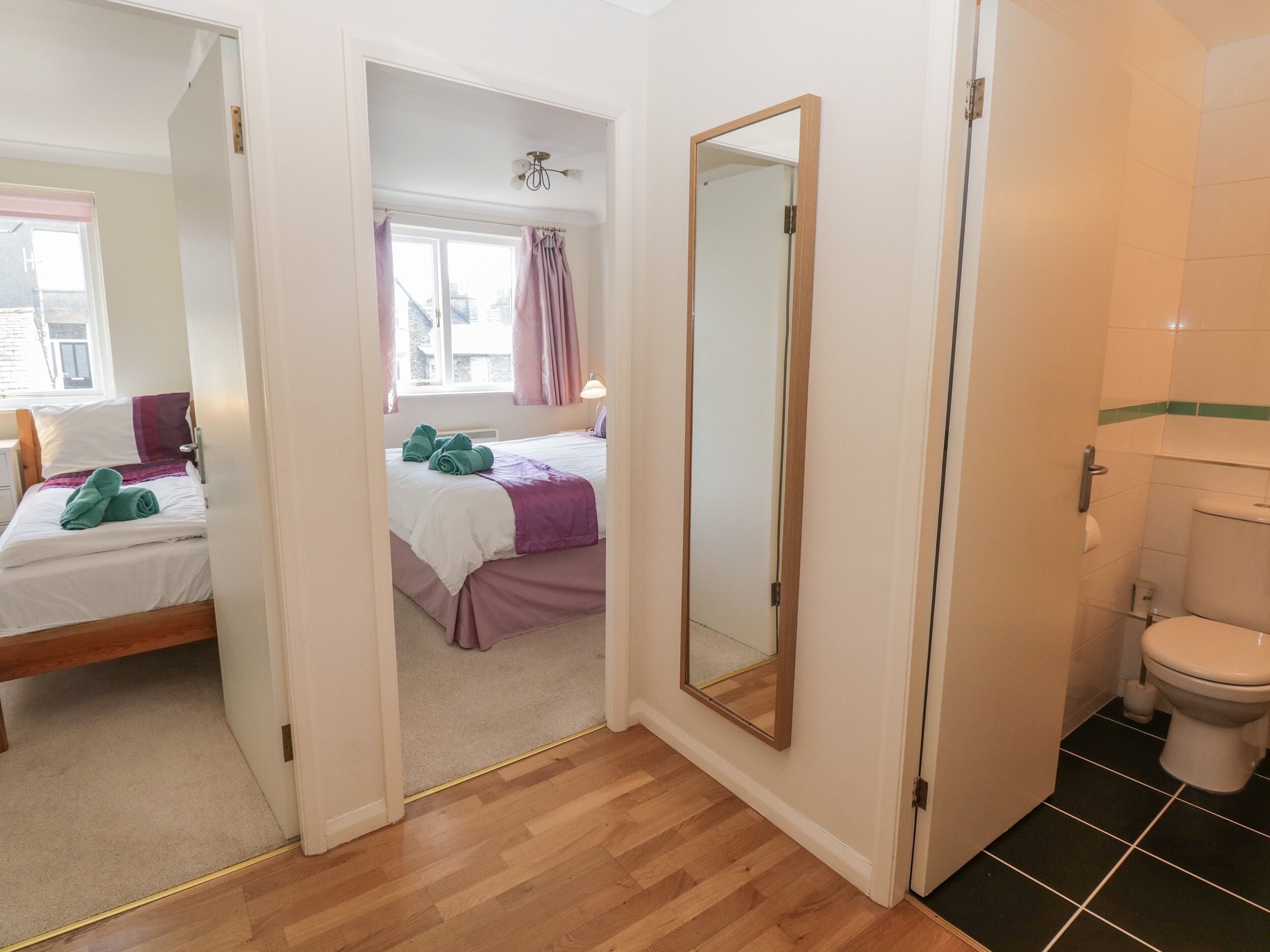 A hotel room with a bed, a bathroom, and a hallway.