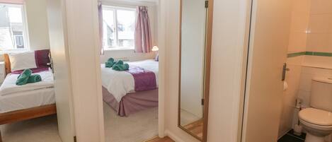A hotel room with a bed, a bathroom, and a hallway.
