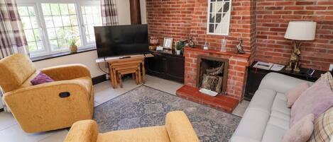 A living room with a brick fireplace, a television, and two sofas.