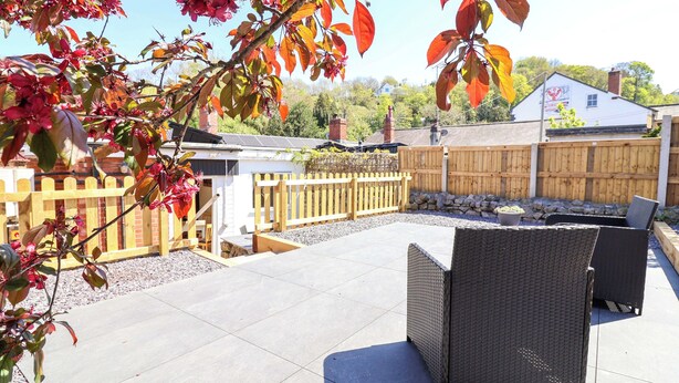 An outdoor patio area with a seating arrangement and a wooden fence. - Ty Cerrig (Rhyl)