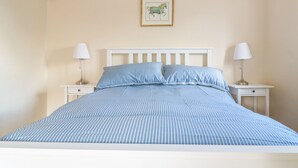 A bed with a striped blue and white bedding, two bedside tables with lamps, and a framed picture on the wall. - Granary 2 (Hereford)