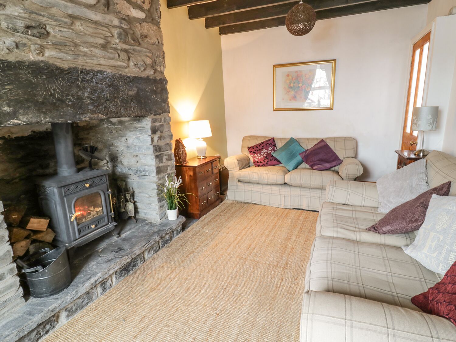A cozy living room with a stone fireplace, a sofa set, and a framed picture on the wall.