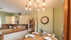 Une cuisine avec des meubles en bois, un dosseret carrelé et une table à manger pour quatre personnes.