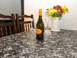 A table with a bottle of Lagioiosa Truzzante wine, two empty wine glasses, and a vase with yellow and red flowers.