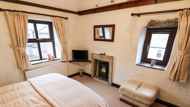 Un dormitorio con cama, televisión, chimenea y ventana con cortinas.