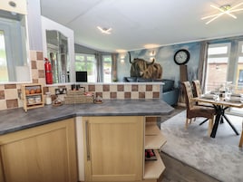 A modern kitchen with a built-in island, a dining area with a wooden table and chairs, and a large clock on the wall.