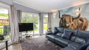 Uma sala de estar moderna com um sofá grande, uma TV de tela plana e um mural de um touro na parede.