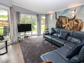 A modern living room with a large sofa, a flat-screen TV, and a bull mural on the wall.