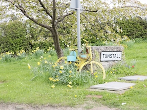 A rural setting with a yellow bicycle, a stone sign reading "TUNSTALL," and a tree with white flowers. - 16 Badgers Retreat (Richmond)