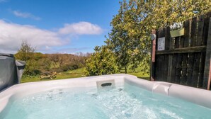 A hot tub with a clear view of the surrounding landscape, including trees and a wooden fence. - Carters (Scarborough)
