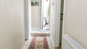 A hallway with a patterned carpet, a door leading to an outdoor area with a bench, and a radiator on the right. - Sea Spray (Eyemouth)